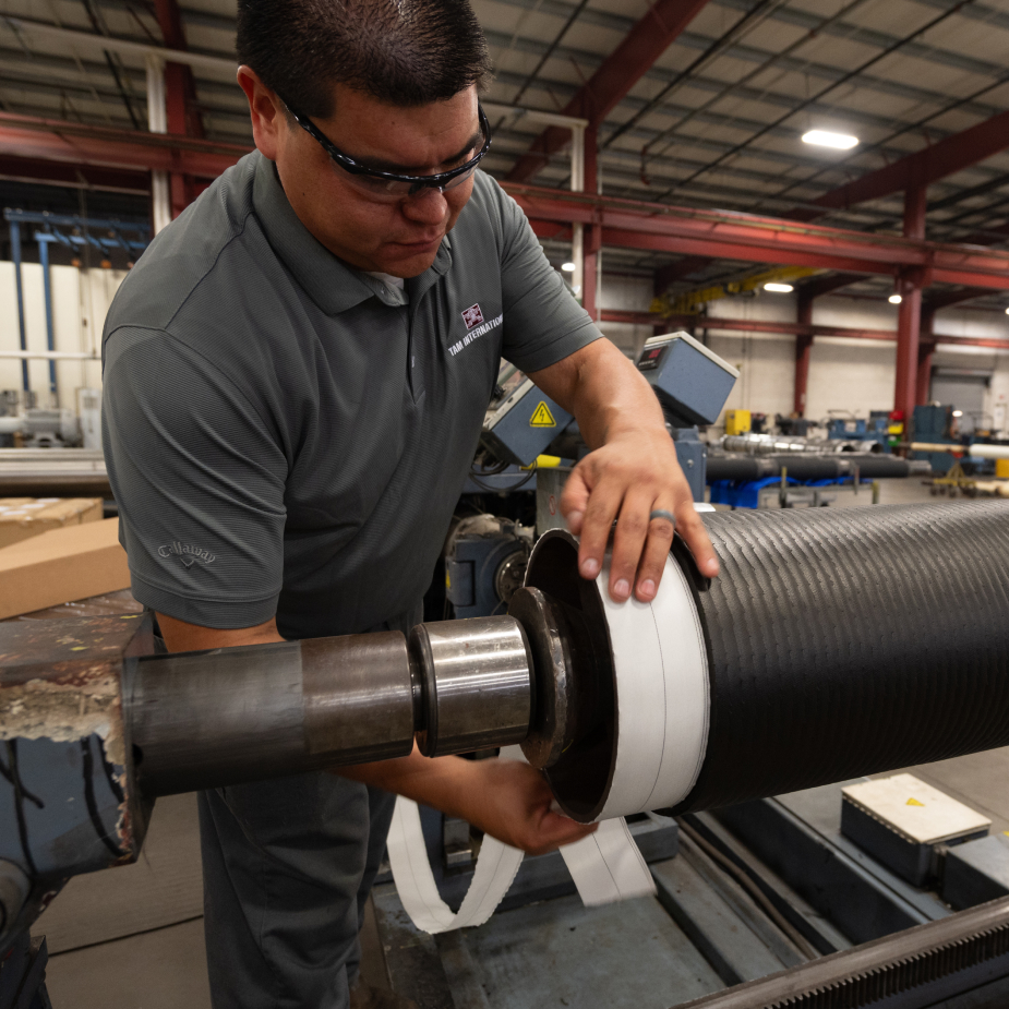 A TAM team member wrapping specialized tape around the piping of a packer