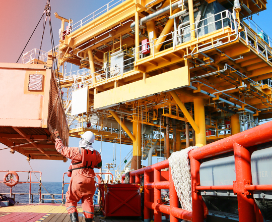 An oil rig worker guiding temporary space unit being lowered onto a platform