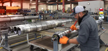 A TAM shop worker tighting casings on packers