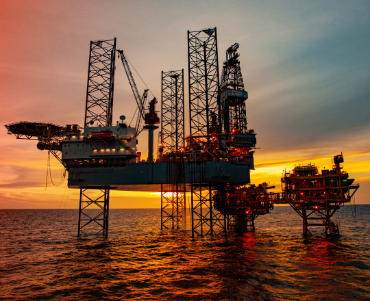 A large oil rig out in the gulf at sunset