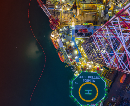 Looking down at an illuminated helicopter pad on an oil rig