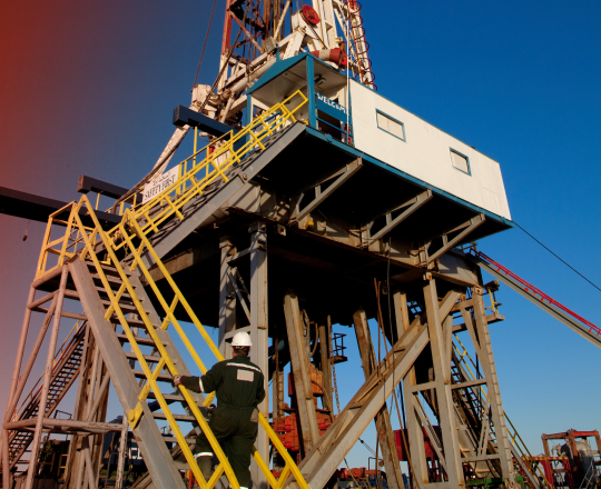 An oil rig worker walking up stairs to the drill tower