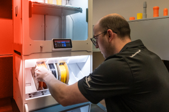 A TAM engineering pulling a spool of orange cable