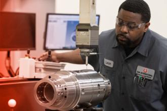 A TAM engineering carefully cutting a piece of machinery with a high powered tool