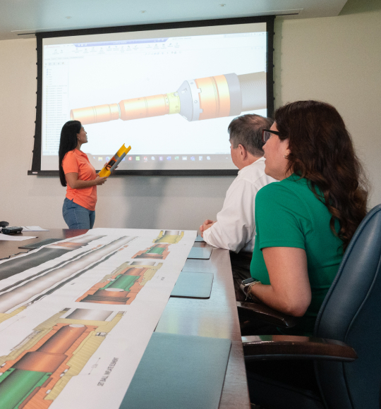 TAM team members sitting around a table looking up at a projector talking about packer designs