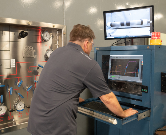 A TAM engineer looking over readings on a machine testing downhole packers