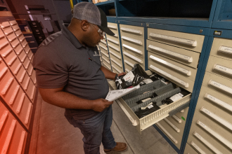 A TAM engineer taking inventory of equipment parts in a drawer