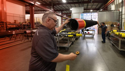 A TAM engineering looking at readings on a small handheld device while checking the inside of a packer