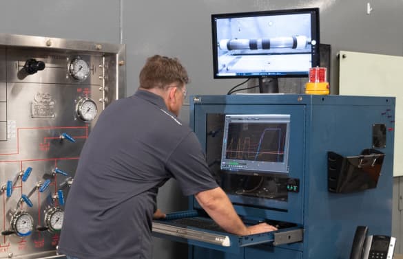 A TAM engineer looking over readings on a machine testing downhole packers