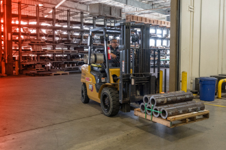 A TAM team member driving a forklift carrying packer parts