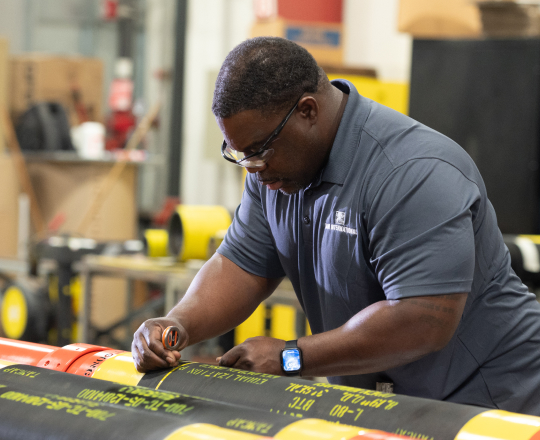 A TAM team member marking downhole packers with yellow safety warnings