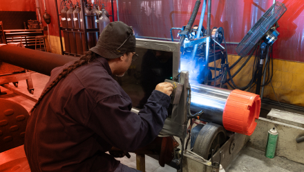 A TAM team member using a laser cutter on a large packer