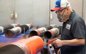 A TAM team member spray painting a pipe orange