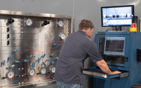 A TAM engineer looking over readings on a machine testing downhole packers