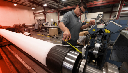 A TAM team member measuring a pipe with a yellow tape measure to ensure accurate measurments