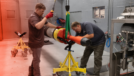 TAM engineers raising a downhole packer in a harness to make adjustments