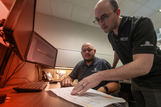 TAM engineers looking over downhole tool designs at a desk next to computers