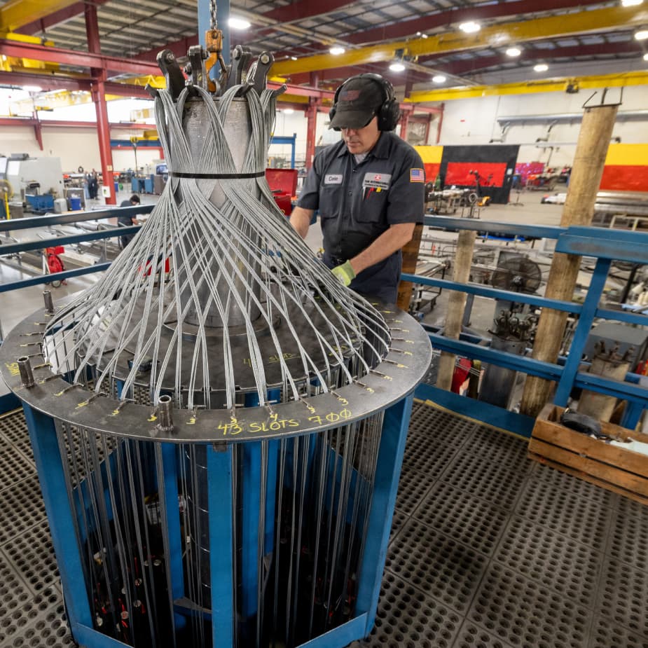 A TAM engineering looking over a large piece of downhole equipment